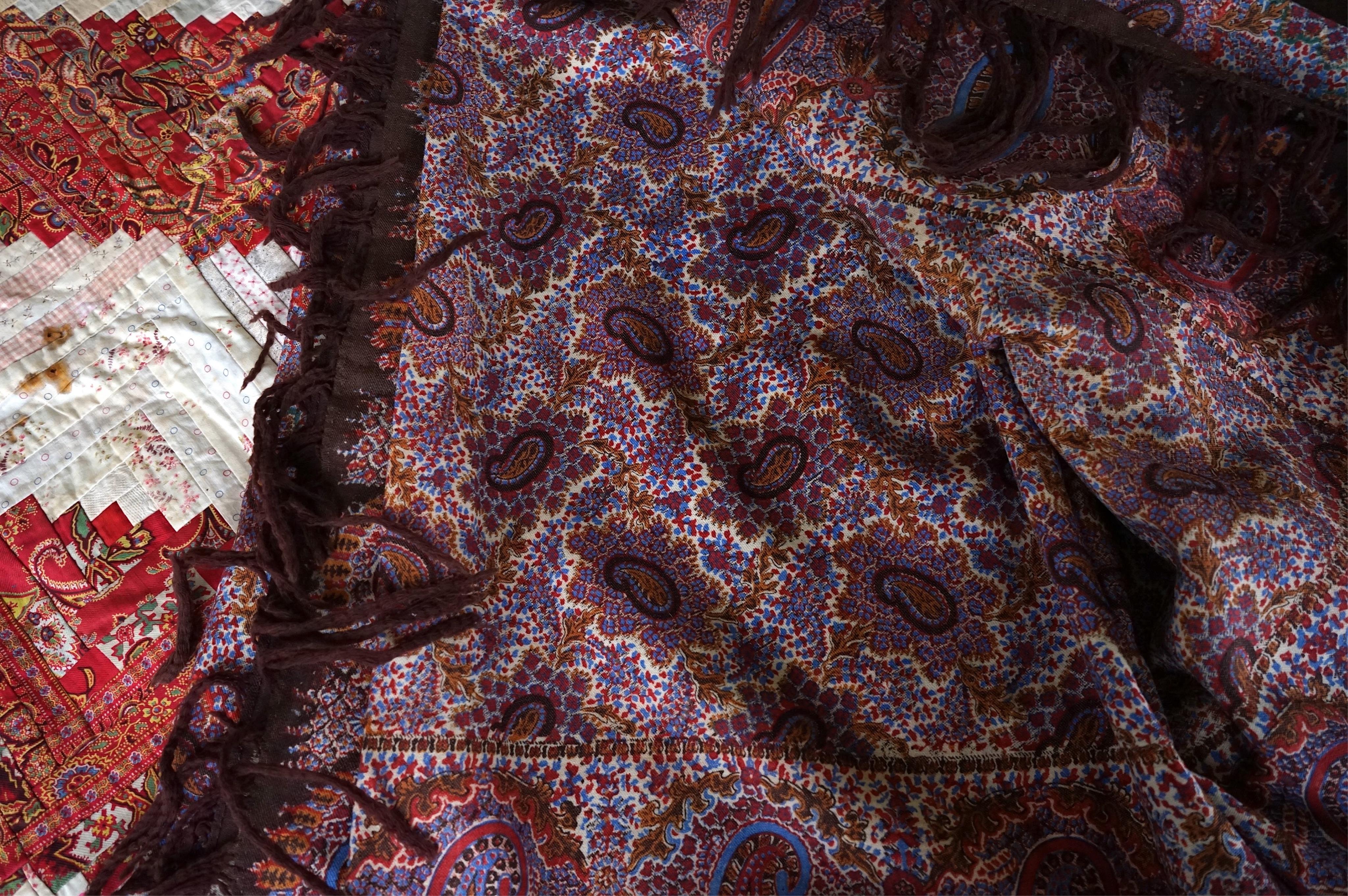 A 19th century printed Paisley summer shawl and an American ‘Log’ patterned patch worked table cover. Cover 152cm x 154cm., Condition - the patchwork has stains and two small holes on the front. The Paisley shawl has a l